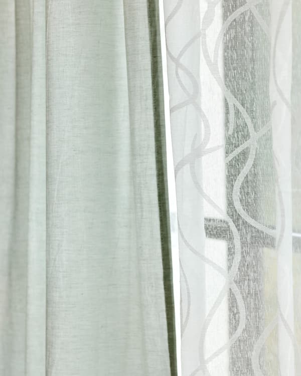 Two fabric curtains hung side by side, one in sheer white cotton, one in light green linen.