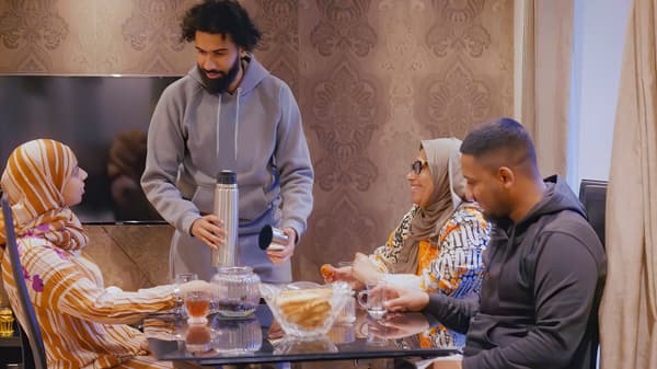 Two generations of a family sitting at a table enjoying a shared meal, laughing and smiling.