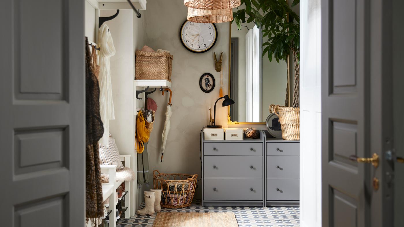 Two grey HAUGA chests of 3 drawers stand in an entryway with a RÅMEBO mirror and a large wall clock on the wall.