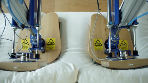 Two IKEA test lab robots mimicking two persons sitting, testing the durability of the sofa.