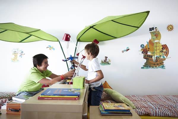Two kids play together over the cabinet that divides their bedroom.