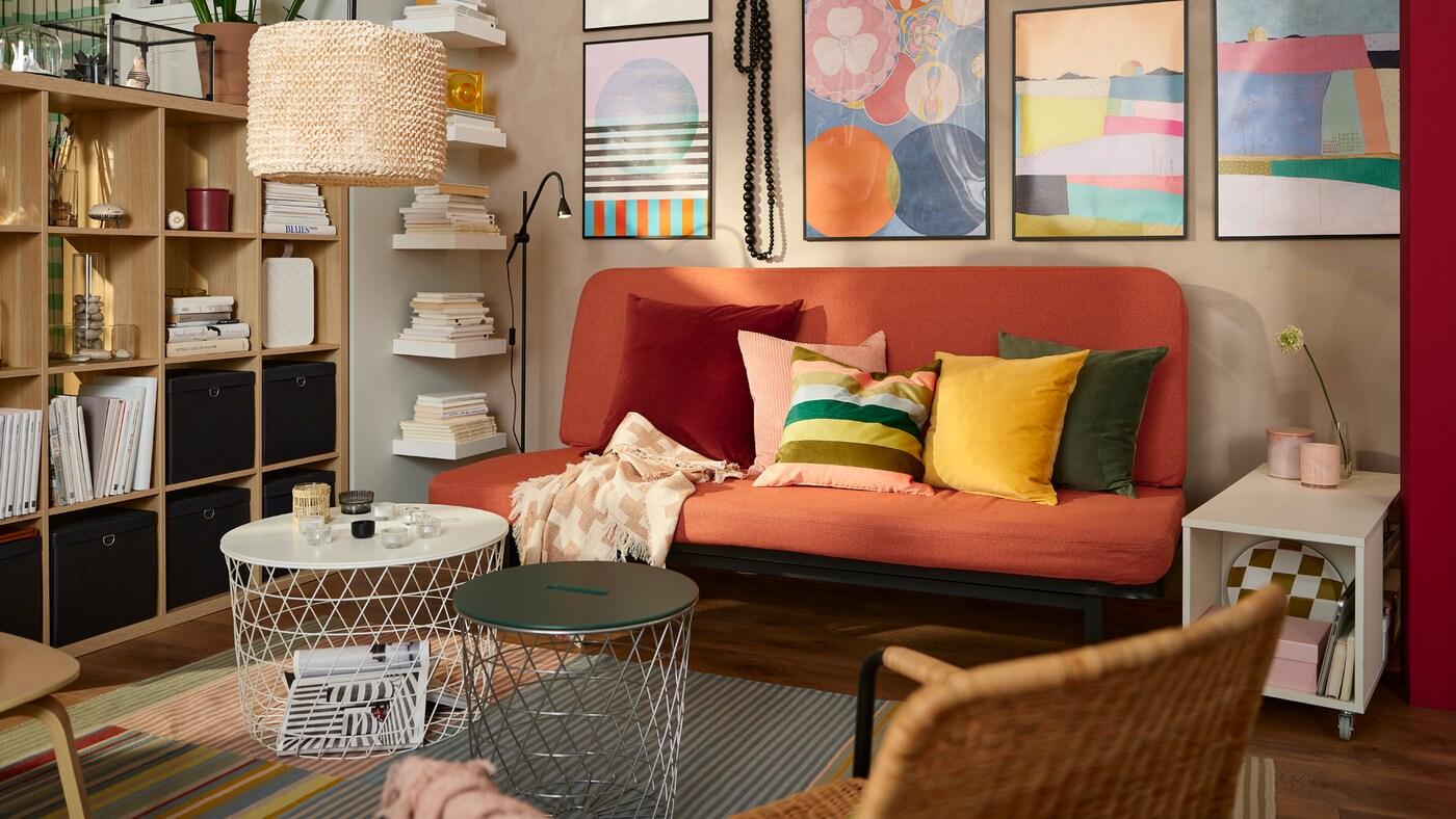 Two KVISTBRO tables in different sizes sit in front of an orange NYHAMN sofa on a stripey rug. A big lamp hangs overhead.