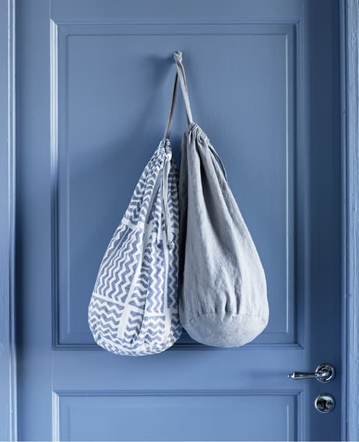 Two laundry bags with different textiles, hanging over the back of a door.