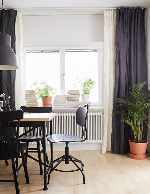 Two layers of white and blue curtains hanging from the ceiling to the floor, elongating the height of the dining room.