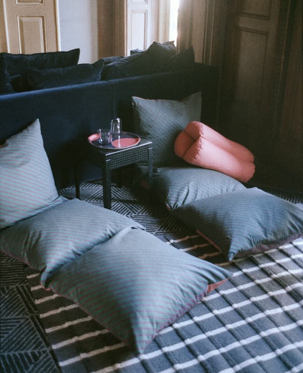 Two long floor cushions and a black metal table.
