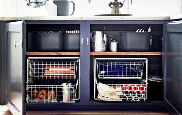 Two open base cabinets in the kitchen reveal wire baskets used to add storage.