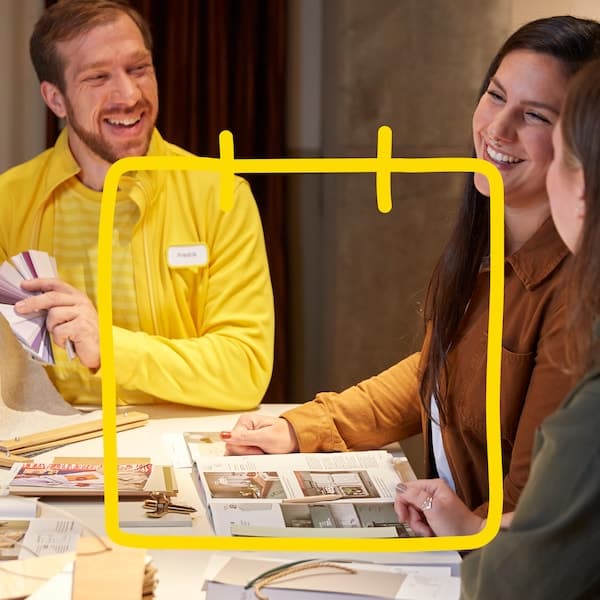 Two people are sitting in a meeting with an interior designer who is showing colours.