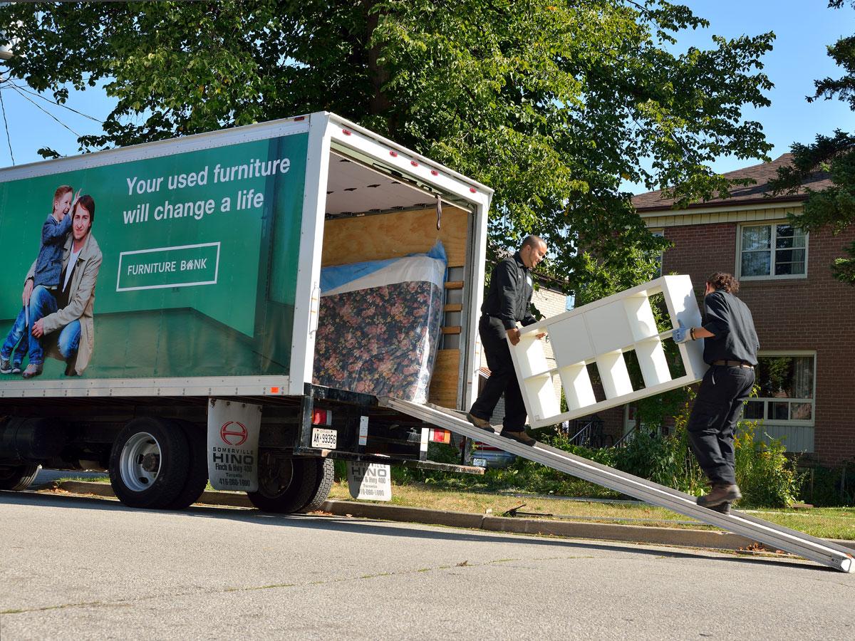 Two people carrying a KALLAX inside a Furniture Bank truck.