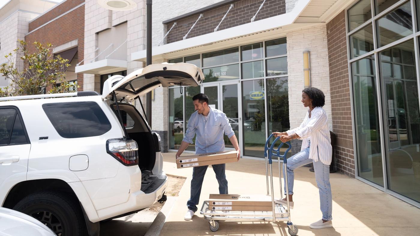 Two people loading IKEA products into the back of  their truck