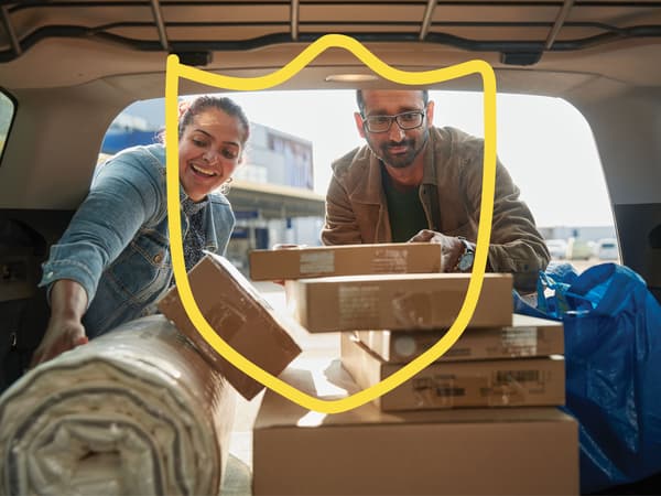 Two people putting IKEA flat-pack boxes in the boot of their car.