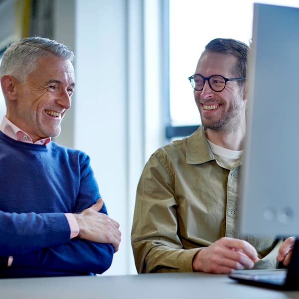 Two people smiling in front of a computer
