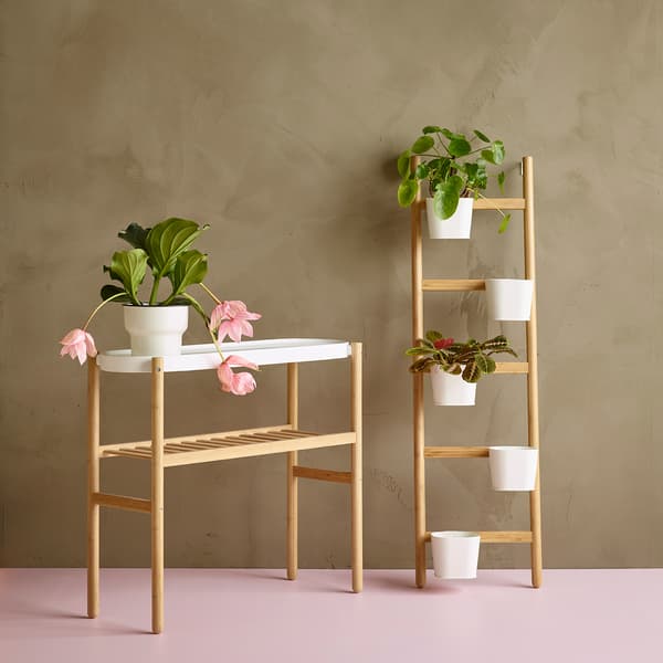 Two SATSUMAS plant stands holding various green plants and pink flowers.