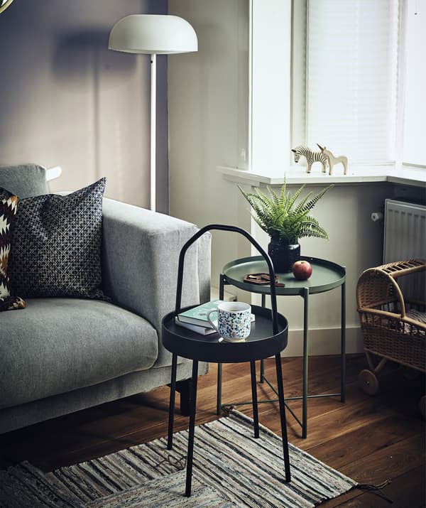Two small, round side tables next to a sofa in a living room.