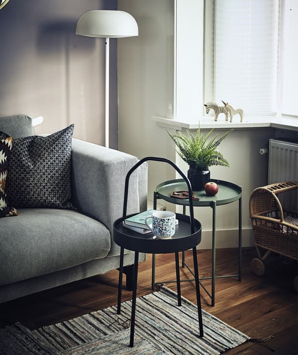 Two small, round side tables next to a sofa in a living room.