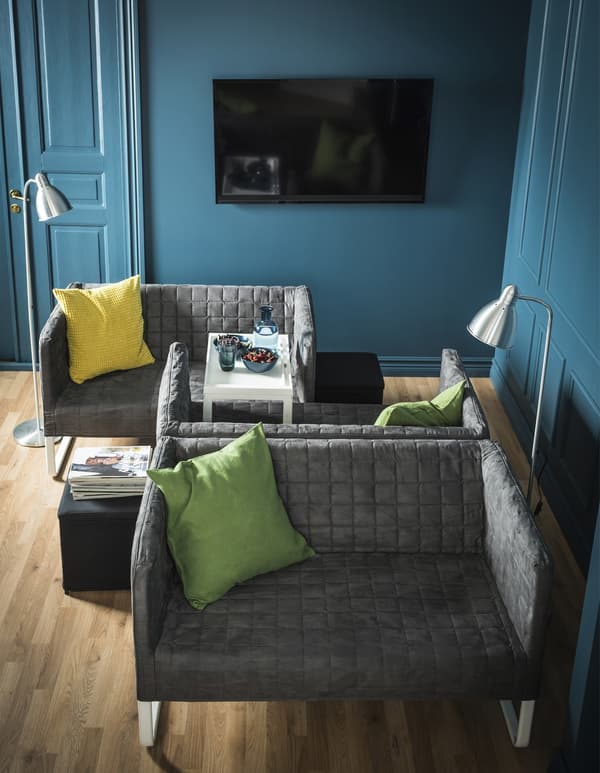 Two small sofas sitting face to face, while one of them has another sofa back to back.