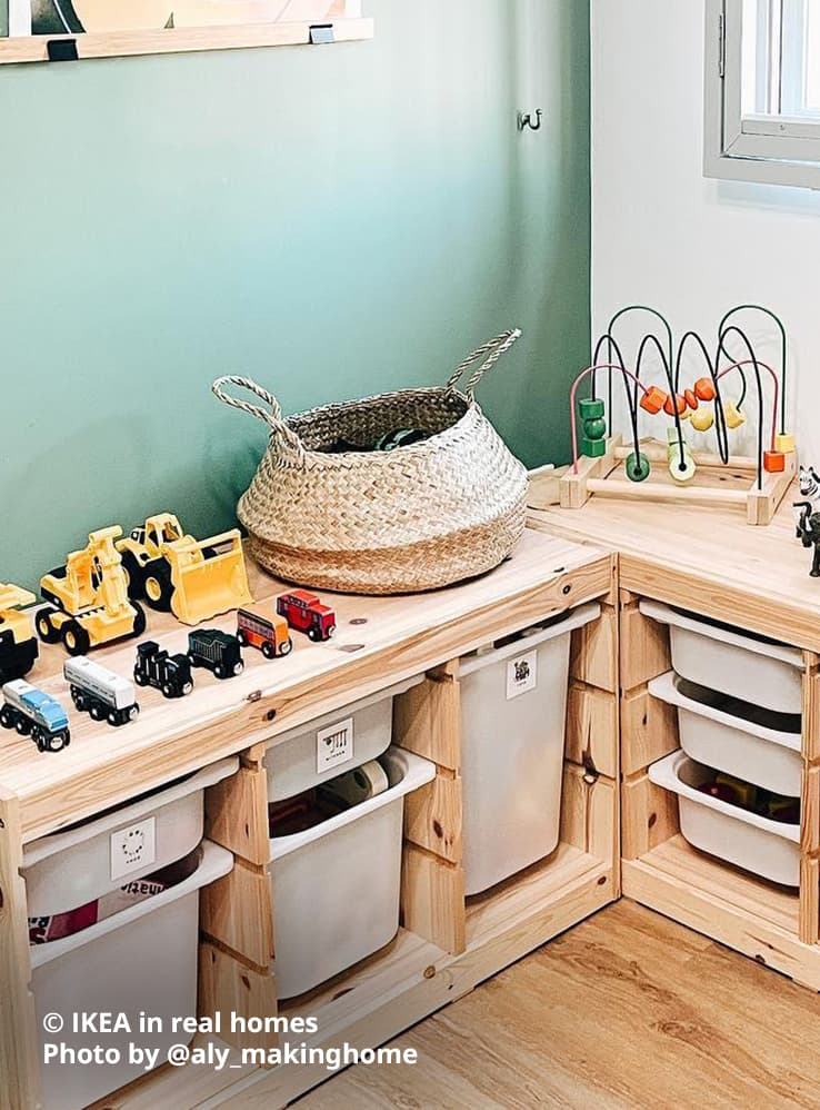 Two TROFAST light white stained pine toy storage combinations in a corner of the home below a window with grills. Several toy trucks and cars, rattan basket and other toys are lined up on top of the storage combinations, with white TROFAST storage boxes in various sizes in each slot with toys. Photo by instagrammer @aly_makinghome for IKEA in real homes.