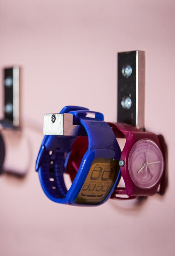 Two watches on a wall hook.