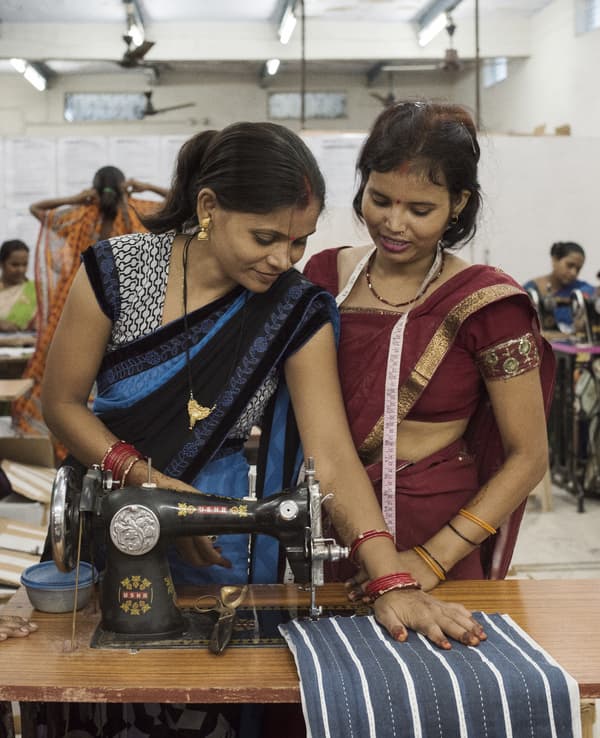 Two women working at a sewing machine.