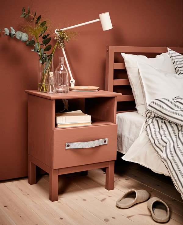 Überarbeiteter Ablagetisch in Kiefer neben einem Bett mit weißer Bettwäsche.
