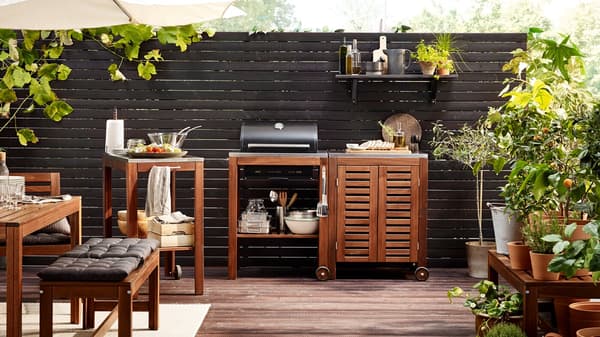 Un aménagement extérieur est composé de tables en bois de la collection ÄPPLARÖ et d’un barbecue GRILLSKÄR avec rangement.
