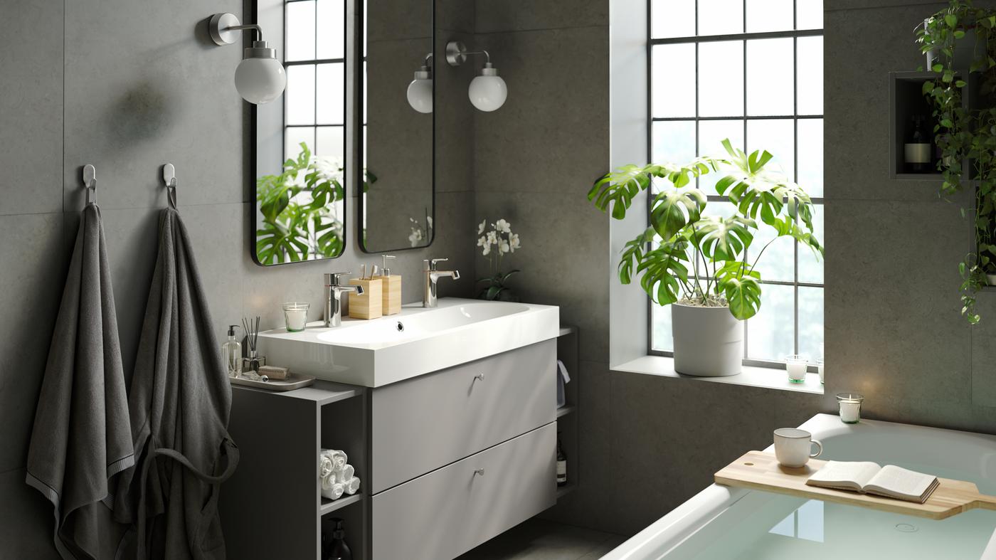 Un bagno rilassante con una vasca moderna ed elegante, un ampio mobile bagno con doppio lavabo, doppi specchi e piante verdi da interno - IKEA
