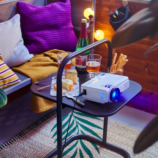 Un banc extérieur avec des boissons et un projecteur installé sur une petite table.