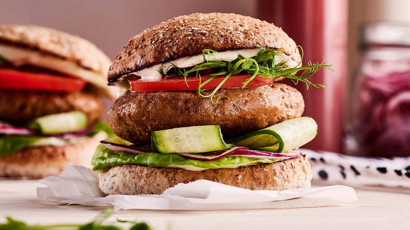 Un burger réalisé avec du haché végétal VÄRLDSKLOK et garni de concombre, oignon rouge, laitue, tomate, jeunes pousses et mayonnaise.