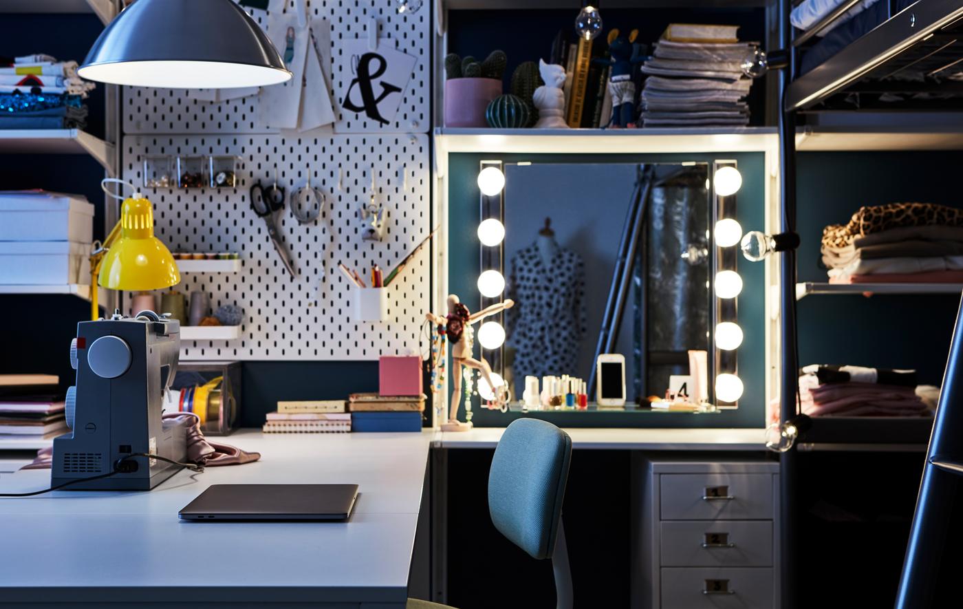 Un coin bureau dans la chambre à coucher avec un bureau, une machine à coudre, une zone maquillage et un panneau perforé IKEA SKÅDIS.