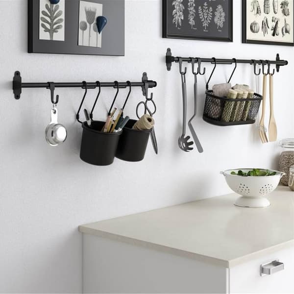 Un coin de cuisine lumineux et minimaliste avec un meuble blanc, des décorations murales et une barre murale portant des tasses et des ustensiles.