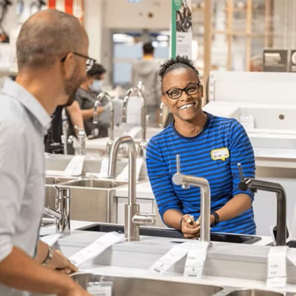 Un collaborateur IKEA aide des clients dans la planification de leur cuisine en magasin.