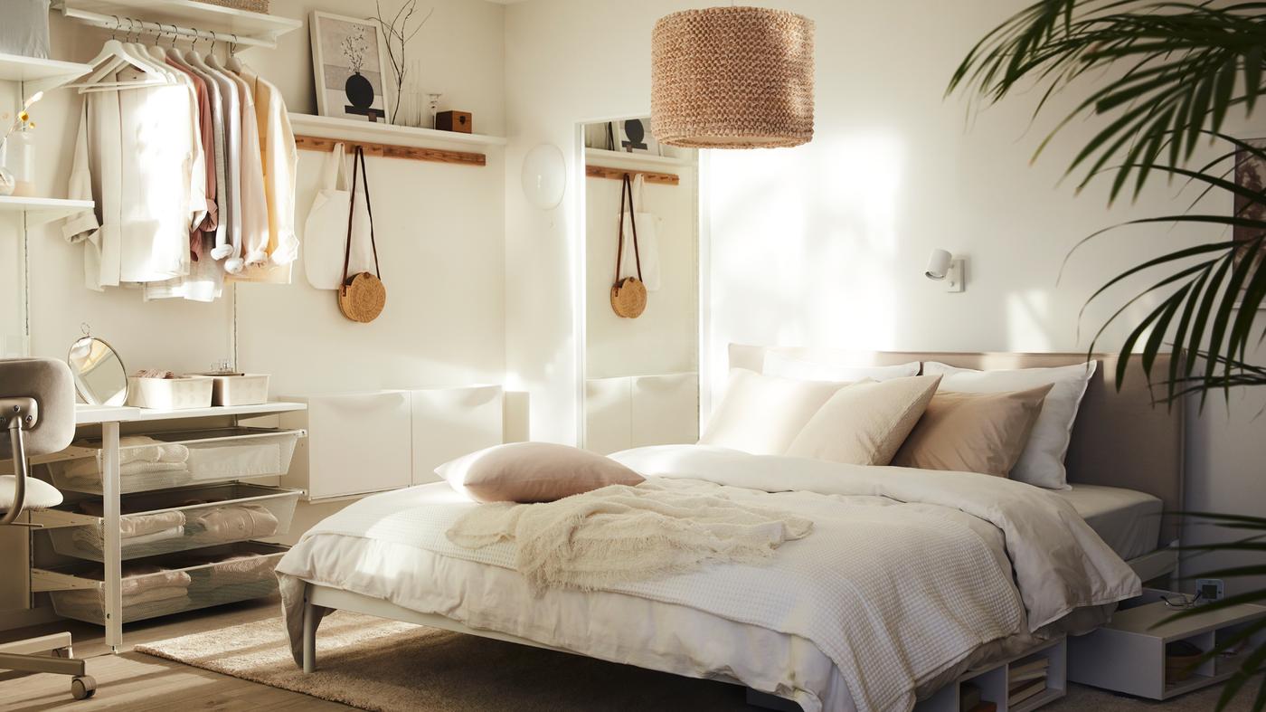 Un dormitorio soleado con una cama KLEPPSTAD con ropa de cama blanca ÄNGSLILJA y una lámpara LERGRYN colgada encima.