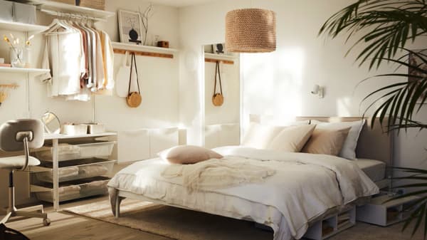 Un dormitorio soleado con una cama KLEPPSTAD con ropa de cama blanca ÄNGSLILJA y una lámpara LERGRYN colgada encima.