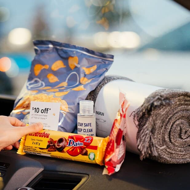 Un ensemble pour ciné-parc comprenant une couverture grise enroulée, des croustilles, du chocolat, des bonbons, du désinfectant pour les mains et un bon pour IKEA.