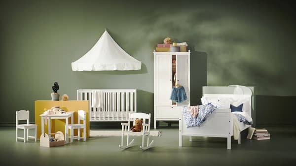 Un espacio con muebles infantiles de madera blancos como cunas, mesas, sillas y clósets.