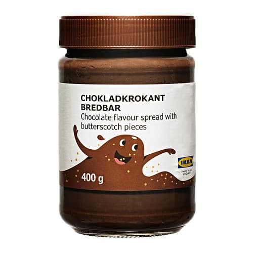 Un frasco café de chocolate untable con trozos de caramelo sobre un fondo blanco.