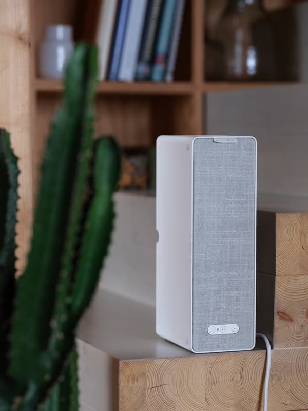 Un haut-parleur d’étagère Wi-Fi SYMFONISK blanc sur un escalier en bois.