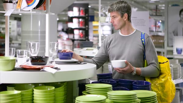 Un hombre con una bolsa amarilla IKEA eligiendo platos,
.