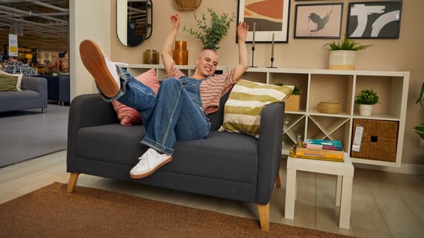 Un hombre sentado en un sofá dentro de la tienda IKEA.