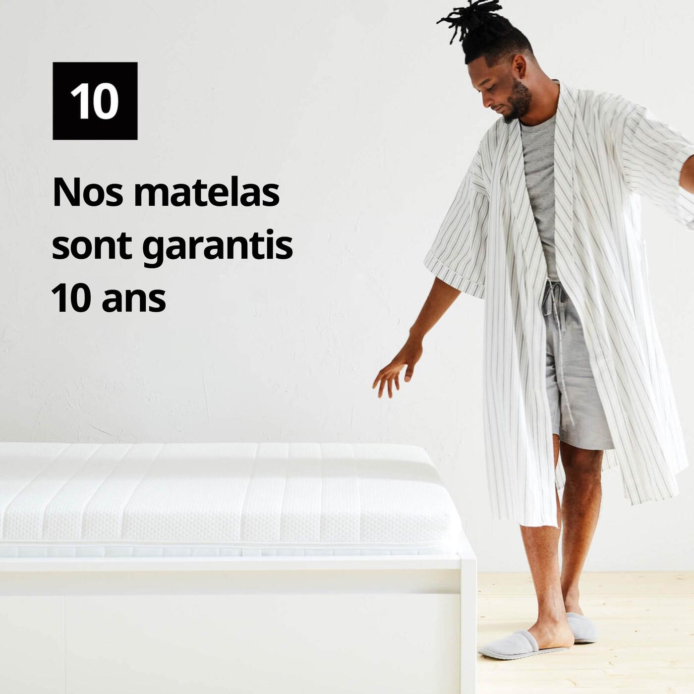Un homme en peignoir se tient à côté d'un matelas et d'un symbole graphique avec le chiffre 10 et le texte "Nos matelas ont une garantie limitée de 10 ans" sur l'image.