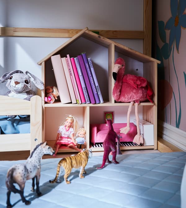 Un lettino e una casa delle bambole che contiene giocattoli e libri nella zona gioco per i bambini - IKEA.
