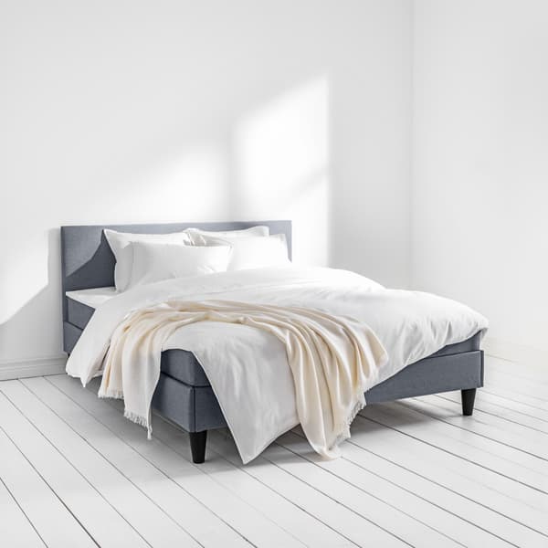 Un letto SÄBÖVIK con rivestimento in tessuto grigio intorno al telaio e testiera nella misura 160x200 nella camera da letto