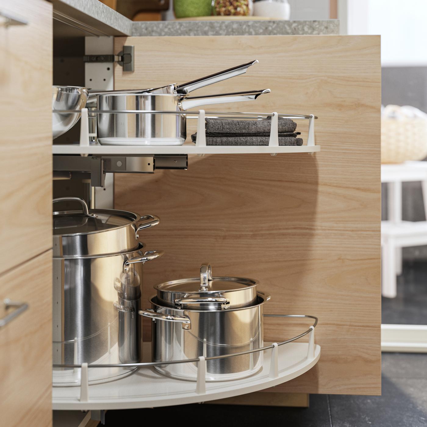 Un mobile base angolare UTRUSTA effetto frassino chiaro ha all'interno un accessorio estraibile che contiene varie pentole con coperchi IKEA 365+ in acciaio inox.