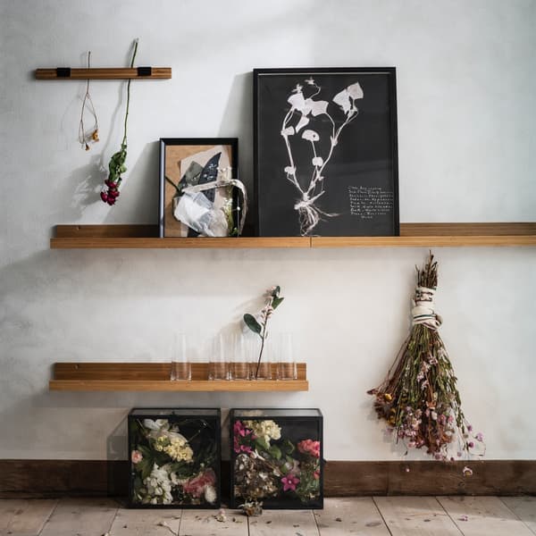 Un mur avec des étagères murales représentant des objets d’art et des fleurs séchées.