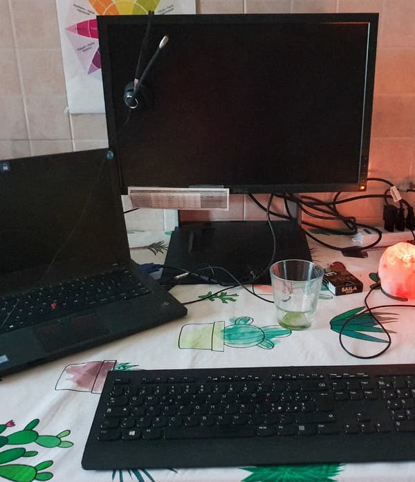 Un ordinateur portable noir, un clavier noir et un écran d'ordinateur noir sur une table dans une cuisine.