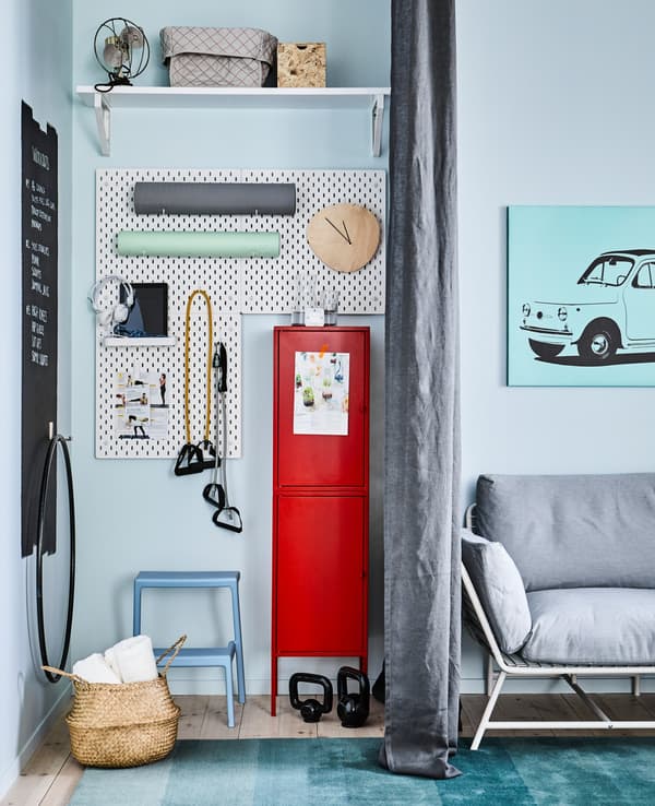 Un petit coin gym aménagé dans un espace de vie, avec un rideau gris comme séparateur pour plus d’intimité.