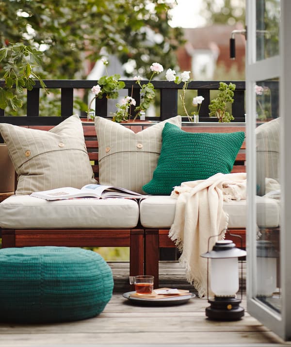 Un petit déjeuner sur le balcon avec des portes ouvertes et beaucoup de coussins, de couvertures et quelques meubles d’extérieur.