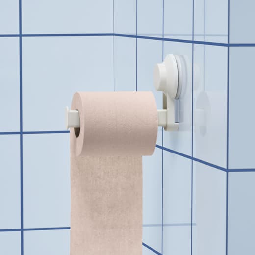 Un rouleau de papier toilette rose suspendu à un porte-rouleau à ventouse sur un mur carrelé bleu.