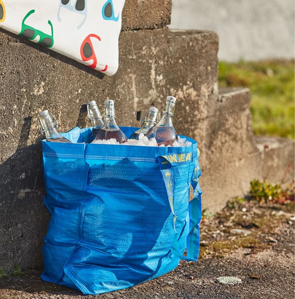Un sac de tri FRAKTA bleu rempli de glace et de bouteilles en verre.