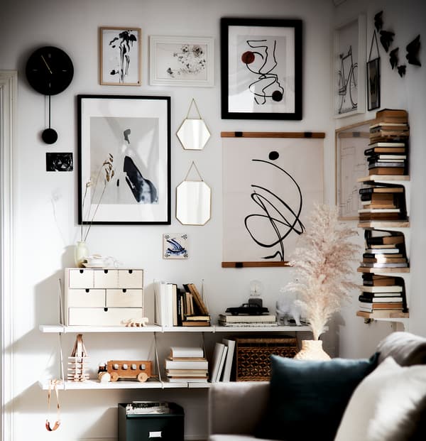 Un salon avec des livres de seconde main, des accents de matériaux naturels et un mur artistique en blanc, noir et avoine.