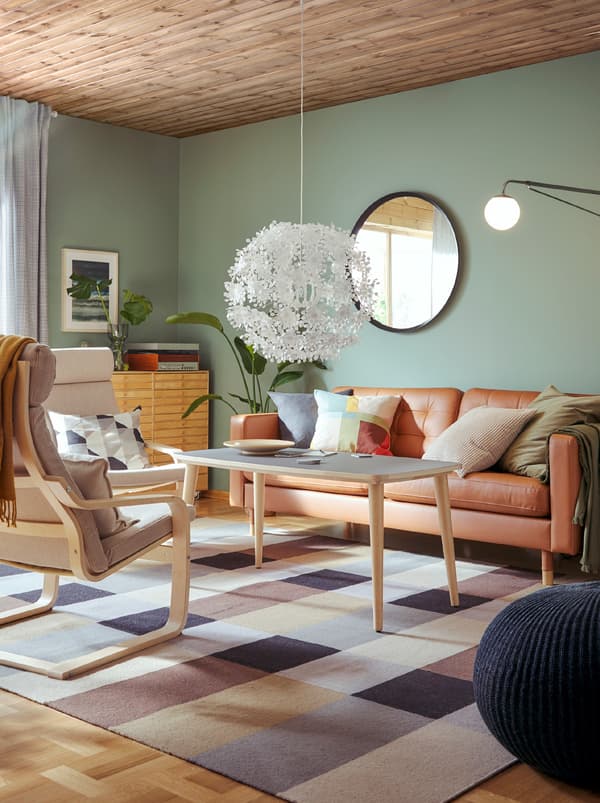 Un séjour avec un canapé, une table basse et deux fauteuils POÄNG en brun clair et blanc avec une structure réalisée en bois courbé léger.